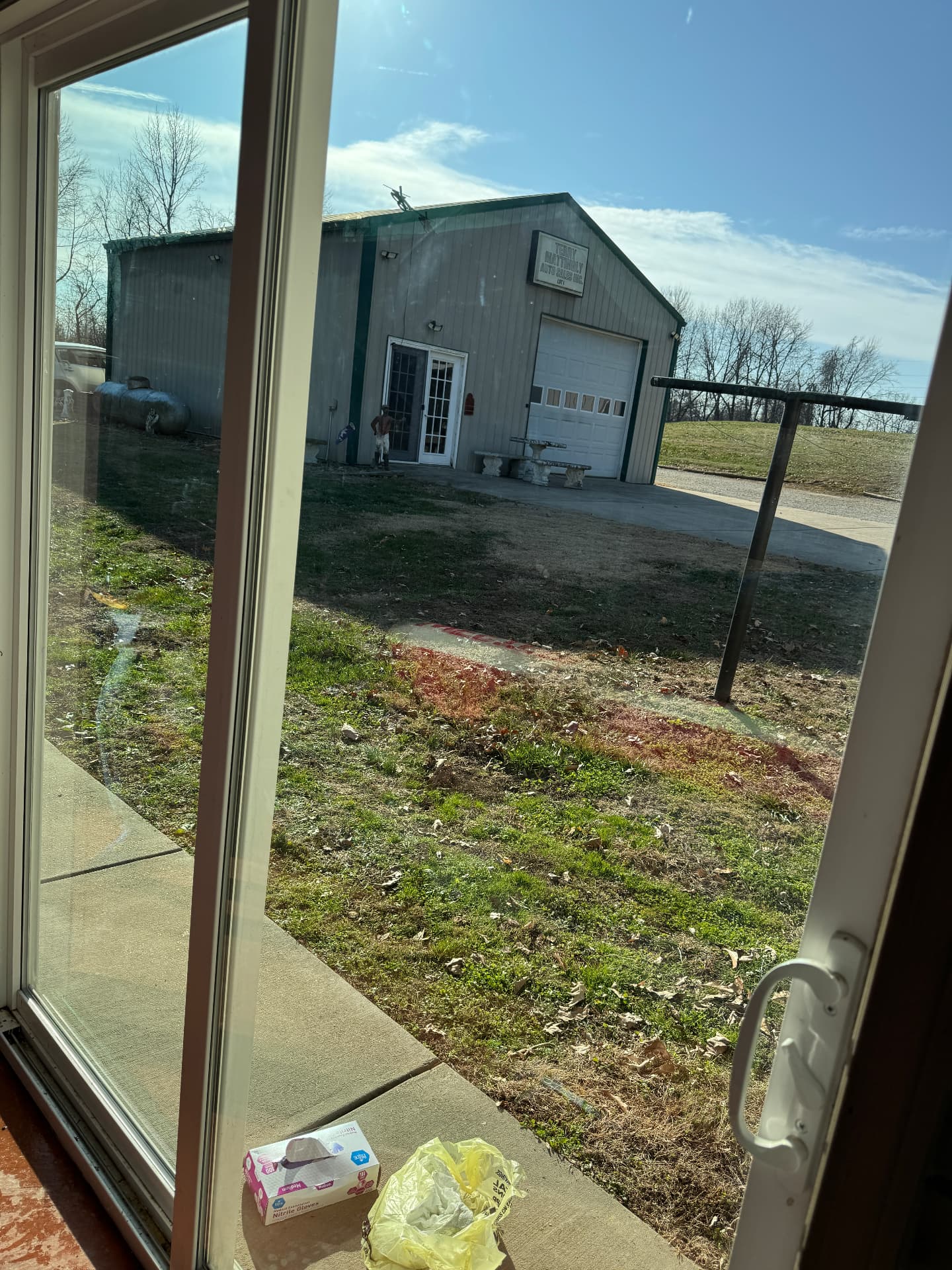 The same glass door panes cleaned clear, with the shop building and yard sharply visible